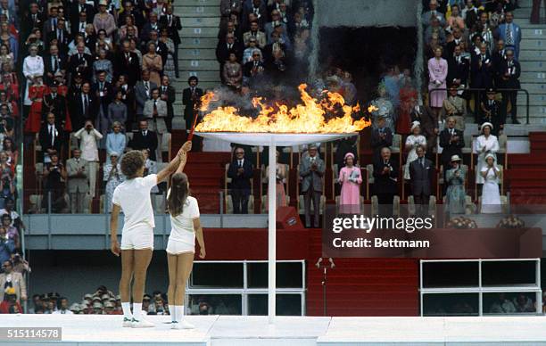 Canadian teenagers Sandra Anderson and Stephen Prefontaine jointly light the Olympic urn in the stadium by passing the flame from their torch 7/17.