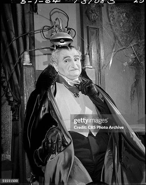 American actor Al Lewis in the role of 'Grandpa' wears evening dress and a cape as he sits in his electric chair in the CBS television situation...