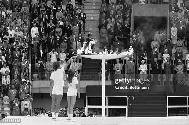 Montreal: Britain's Queen Elizabeth II rises to her feet as the Olympic flame is passed on to the urn in Olympic Stadium, during opening ceremonies...