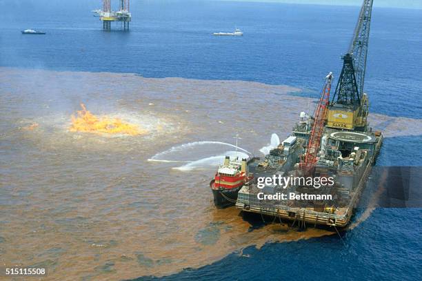Bay of Campeche, Gulf of Mexico: Workers on barge spray chemical dispersant on excess oil around burning well of the Ixtoc I well here recently. The...
