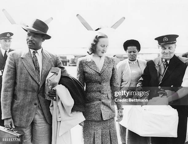 Seretse Khama, 29-year-old exiled chief designate of the Bamangwato tribe, with his ex-London wife Ruth walk from the giant flying boat that brought...
