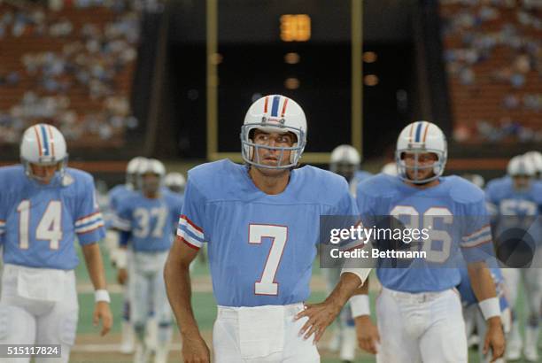 Houston Oilers quarterback Dan Pastorini stands on the filed with his hand on his hip.