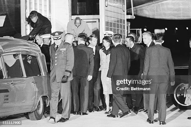 Mrs. Jacqueline Kennedy, her clothing splattered with the blood of her assassinated husband, watches as the body of the dead President is placed in...