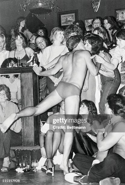 Los Angeles, California: A male stripper and "ladies only" crowd pleaser collects a dollar tip in exchange for kissing a member of the audience...