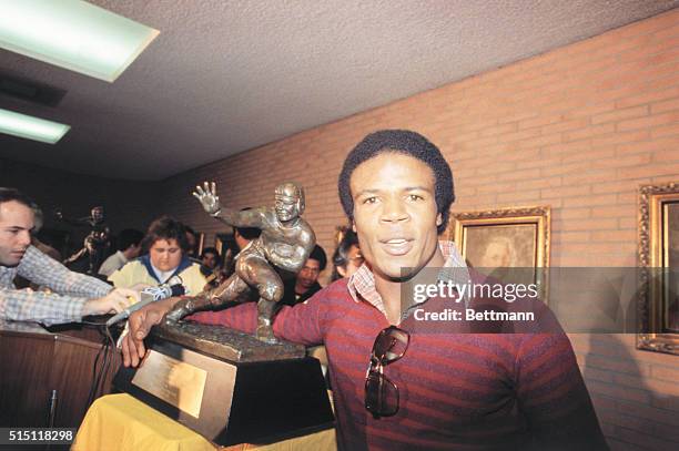 S Charles White, winner of the 1979 Heisman Trophy, puts his arm around the same trophy won by O.J. Simpson during press conference 12/3. White, the...