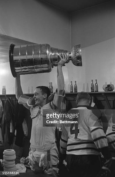 Frank Mahovlich of the Toronto Maple Leafs raises the Stanley Cup over his head in a victory salute in the Toronto dressing room after defeating the...
