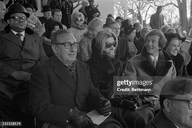 Presidential adviser Henry Kissinger, Nancy Maginnes, Pat Boone, and Mrs. Boone occupy the Presidential reviewing stand in front of the White House...