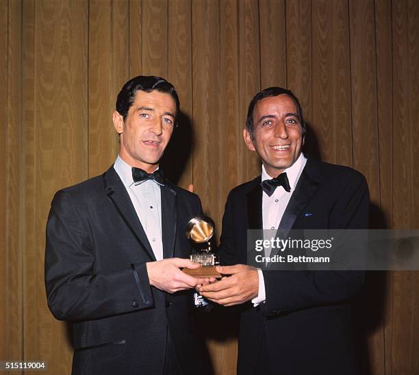 Tony Bennett, singer, with Tom Rogan, Liberty Records Executive, to whom he presents the Grammy Award that was given to the Fifth Dimension Group for...