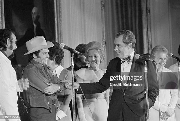 Washington: Wearing an oversize green satin bow-tie which he borrowed from a White House usher, President Nixon jokes with country-western singer...