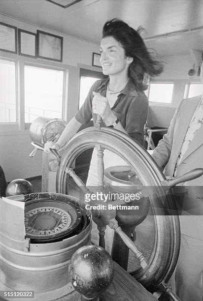 Jacqueline Kennedy Onassis takes a turn at the wheel on board a Staten Island ferry here July 30th as she returns to Manhattan following a tour of...