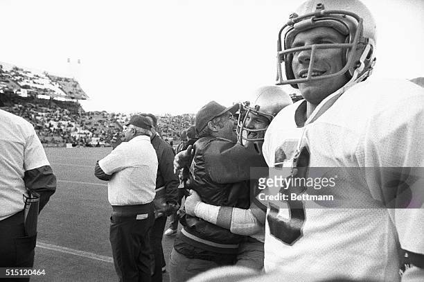 While Notre Dame quarterback Joe Montana begins to smile, coach Dan Devine turns and hugs one of his players as the last minute on the clock ticks...