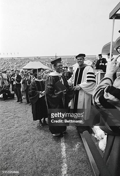 Comedian Bill Cosby shakes hands with University of Massachusetts Chancellor Randolph W. Bromery after receiving his Doctor of Education degree,...