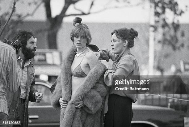New York: Faye Dunaway adjusts furs on a model as producer Jon Peters leans in to give her some advice. Scene was the outdoor setting where Mr....