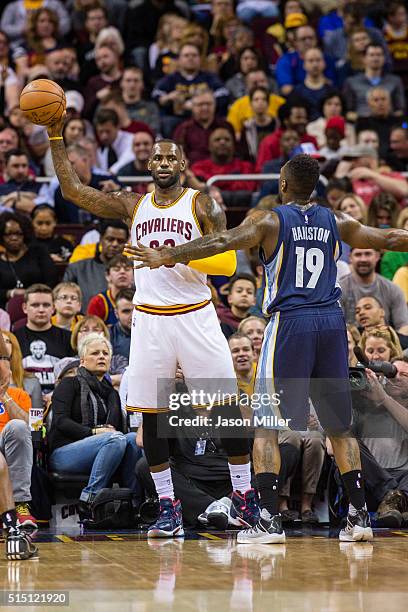 LeBron James of the Cleveland Cavaliers looks to pass around P.J. Hairston of the Memphis Grizzlies during the first half at Quicken Loans Arena on...