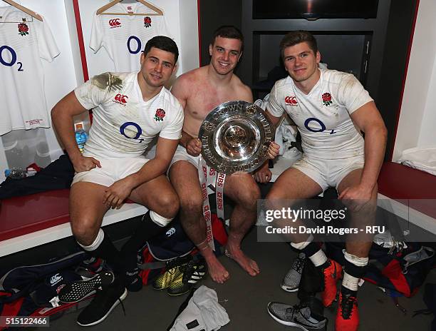 Ben Youngs, George Ford and Owen Farrell of England pose with the Triple Crown trophy in the dressing room after the RBS Six Nations match between...