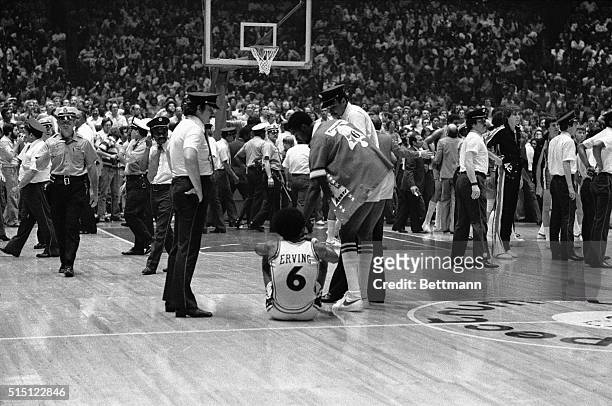 Philadelphia 76ers' Julius Erving is helped from the floor by teammate Joe Bryant after police and Spectrum security cleared the court after a melee...