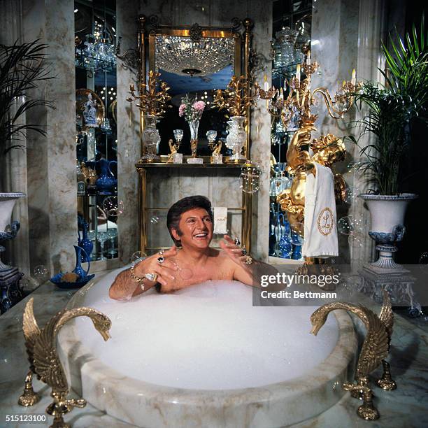 Liberace spoofs a day in his own life during a television special, including a scene where he baths in his $55,000 marble bathtub.