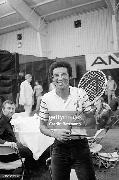 New York: Tennis great Arthur Ashe seems almost out of place with street clothes and a tennis racket, but he was on hand at the U. S. Open Tennis...