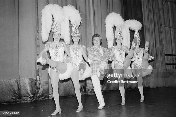 New York: Entertainer Liberace practices a few high kicks with four members of the world famous Radio City Rockettes during backstage visit at the...