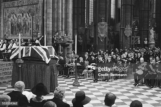 Prince Charles is shown reading the lesson from the lectern, with members of the Royal Family seated below him. The Queen, Duke of Edinburgh, Queen...