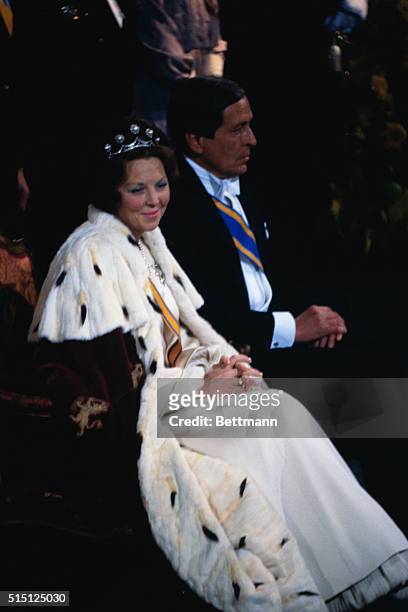 As Prince Claus looks on, Queen Beatrix of the Netherlands sits upon her throne during her investiture in the New Church in 1980.