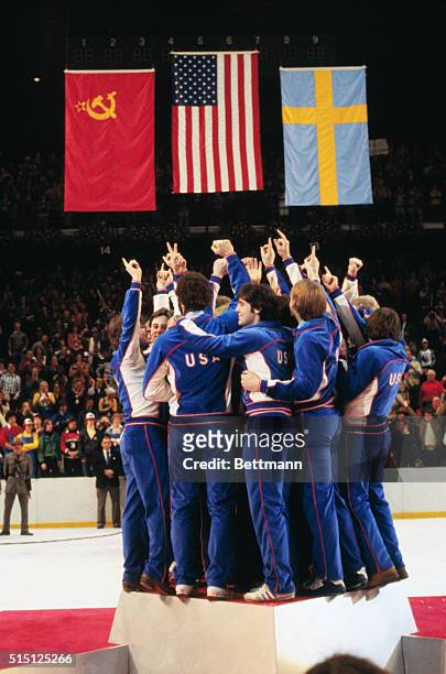 Lake Placid, New York: The American Olympic Hockey Team crowds onto the center podium with fingers pointed skyward designating their "Number One"...
