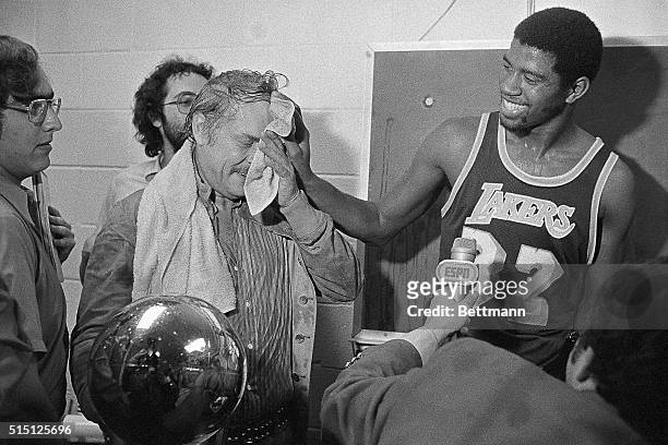 Magic Johnson wipes the face of Lakers' owner Dr. Jerry Buss after he poured champagne over him after the Lakers beat the Sixers 123-107 to win here,...