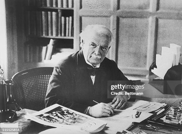 British statesman David Lloyd-George, leader of the Liberal Party, seated at his desk with pen in hand.