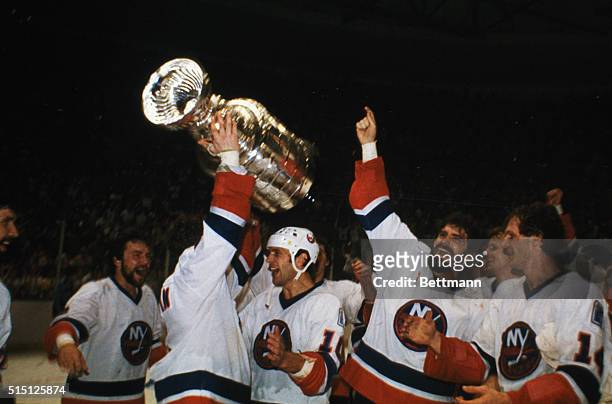 Uniondale, New York: Islanders Captain Dennis Potvin holds the Stanley Cup aloft as he and teammates celebrate their Cup victory over the...