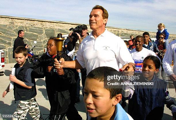 Actor Arnold Schwarzenegger carries the Special Olympics Flame of Hope as he runs with intellectually disadvantaged children at the start of the Law...