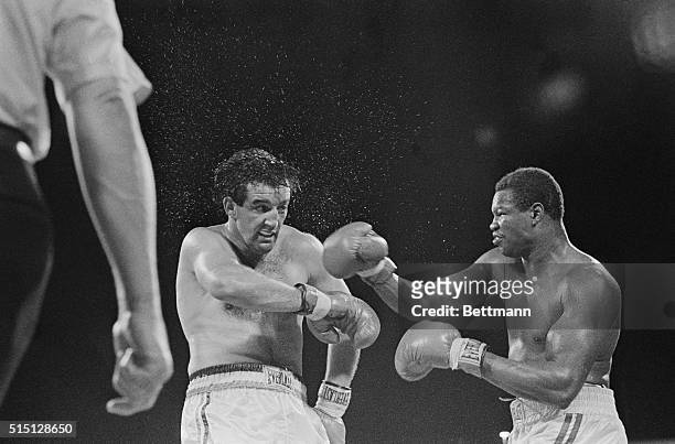 Droplets of water flying from his head, Gerry Cooney shows the effect of a right hook by WBC heavyweight champ Larry Holmes, during their 15-round...