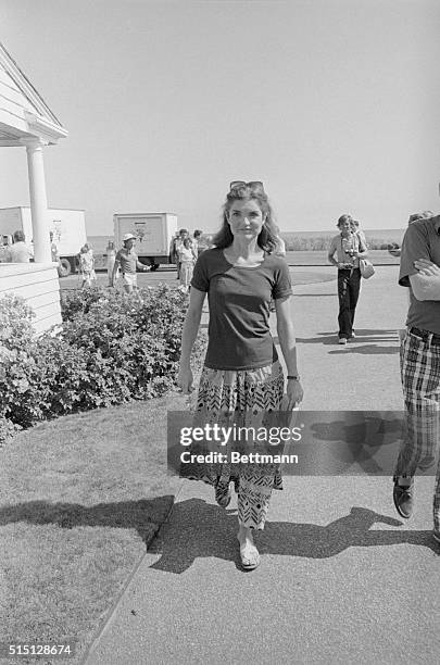 Jacqueline Onassis wearing a jersey print peasant skirt and sandals, walks in the Kennedy Compound during the gathering of some Kennedy family...