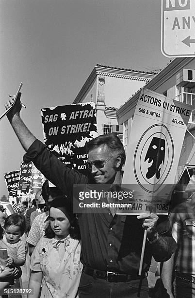 Hollywood, CA- Actor Charlton Heston waves as he carries his picket sign as members of the striking Screen Actors Guild picket Paramount Picture's...