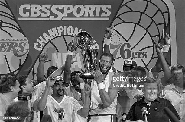 Inglewood, California: Victorious Los Angeles Lakers players, with Kareem Abdul-Jabaar holding up the championship trophy, cheer after their 104-114...