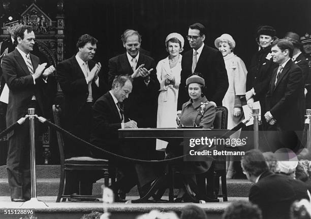 Canadian Prime Minister Pierre Trudeau signs a proclamation in the presence of HRH Queen Elizabeth II in Ottawa, Canada Also in attendance are...