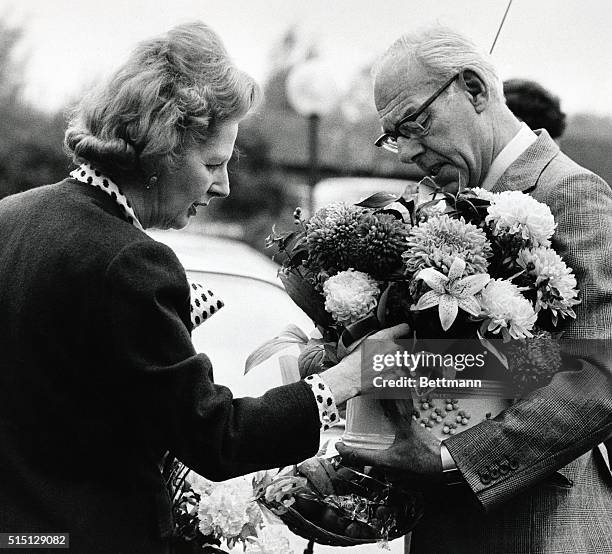 Britain's Prime Minister Margaret Thatcher with husband Denis carrying flowers and gifts, 10/28, as they arrive at Stoke Mandeville Hospital, England...