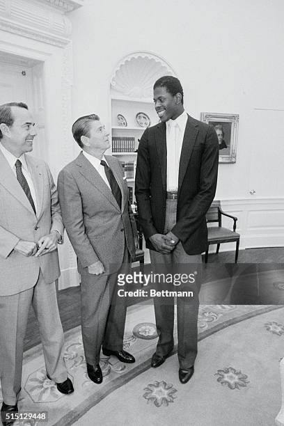 Washington, D.C.: President Reagan talk with Georgetown University basketball star Patrick Ewing in the Oval Office. Ewing is working as a summer...