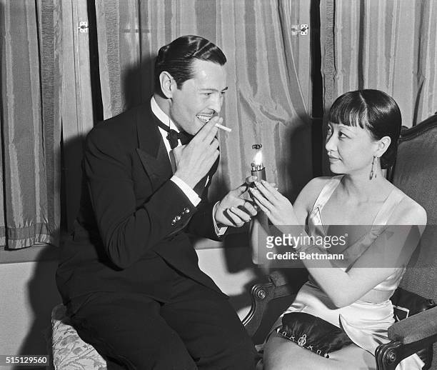 Stars at a Party. Anna May Wong assists Ivan Lebedef with a light during the party given by Harry Lachman, motion picture executive, in his home in...