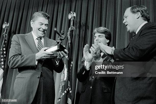 Washington: President Reagan, 6 feet 1 inch tall, is applauded after he was presented a replica of the Heisman Trophy by Andrew Corbett , chairman of...