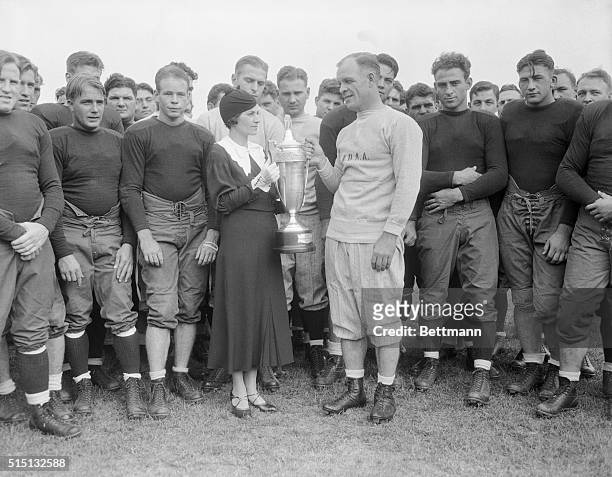 Mrs. Knute Rockne, the widow of the famous coach, is shown presenting the All American Captain's Cup for 1932 to Coach Hunk Anderson of Notre Dame...