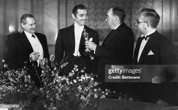 Clark Gable , is shown being presented a gold statuette by Irvin S. Cobb, noted writer, for his acting in It Happened One Night, the Columbia film...
