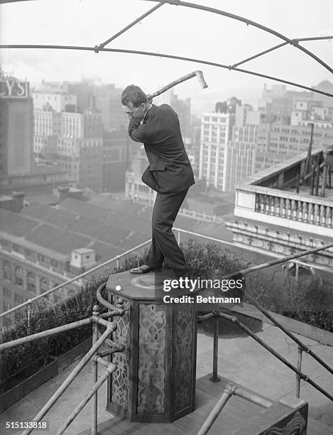 Photo shows Willie McFarlane the world open Golf Champ, driving off the roof of the Hotel McAlpin, with the club which was made for him by a crippled...