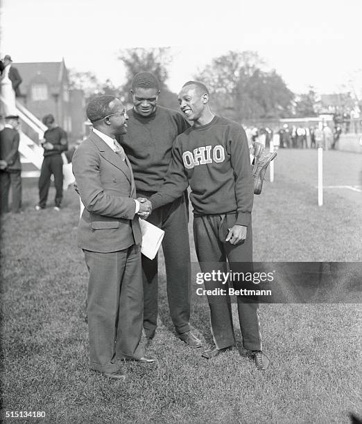 Eddie Tolan, great sprinter of a few years ago, congratulating Jesse Owens of Ohio State, after the latter had smashed three world's records, and...