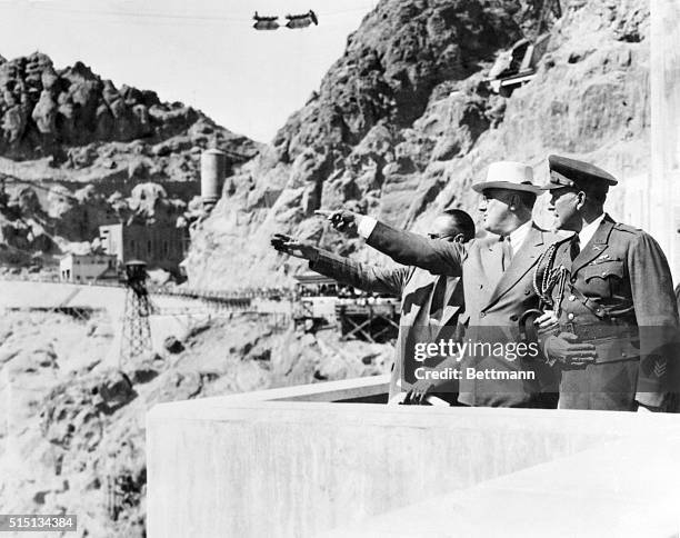 President Roosevelt, high up on one side of the huge Boulder Dam at Boulder City, Nevada, points to one feature of the mighty structure, and asks a...
