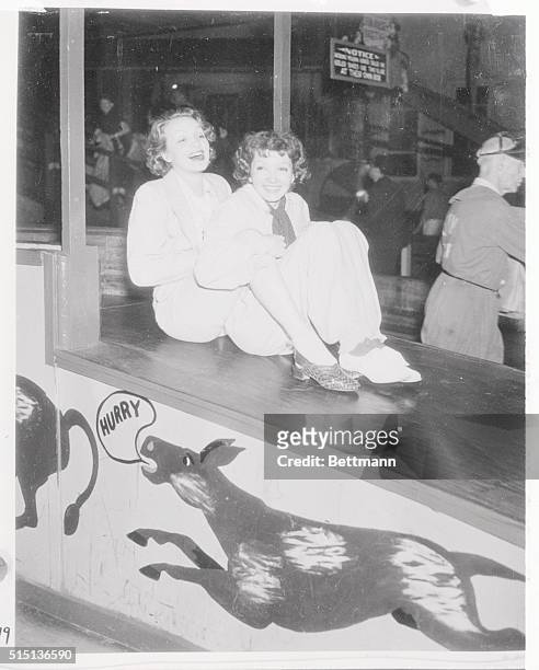 You've heard of shooting stars; but here's a couple of sliding stars. They are Marlene Dietrich, , and Claudette Colbert, as they appeared at a...
