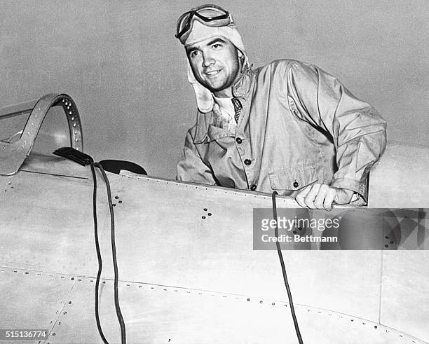 Howard Hughes in the cockpit of an airplane in a leather flight helmet and goggles.