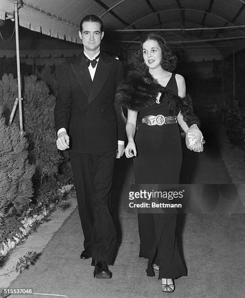 Gloria Baker, social registerite daughter of Mrs. Margaret Emerson, with Howard Hughes, millionaire motion picture producer, pictured leaving The...