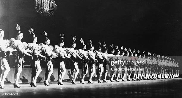 New York, New York: The Rockettes on stage at Radio City Music Hall in their classic chorus line stance, beautifully decorated with elaborate chapeau.