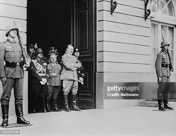 Standing in the doorway of the Chancellory in Berlin, Chancellor Hitler and Nazi and state officials watch an impressive military parade staged in...