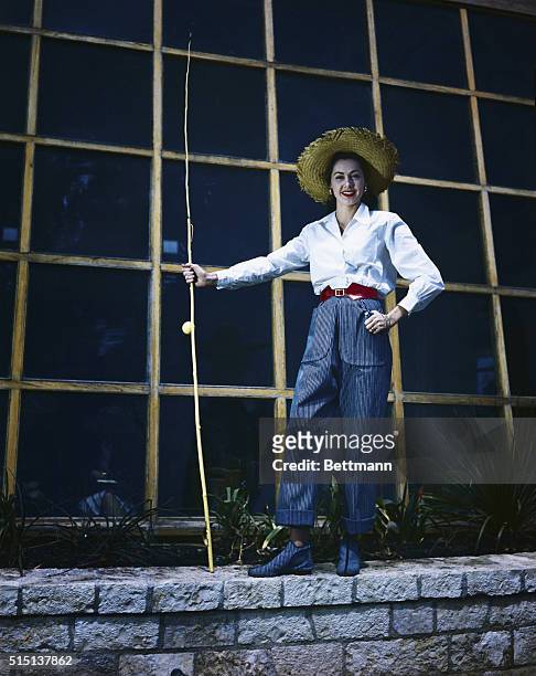 Neiman-Marcus model wears Claire McCardell's fishing slacks of bright blue denim worn with a classic little boy's shirt of white. The outfit is shown...